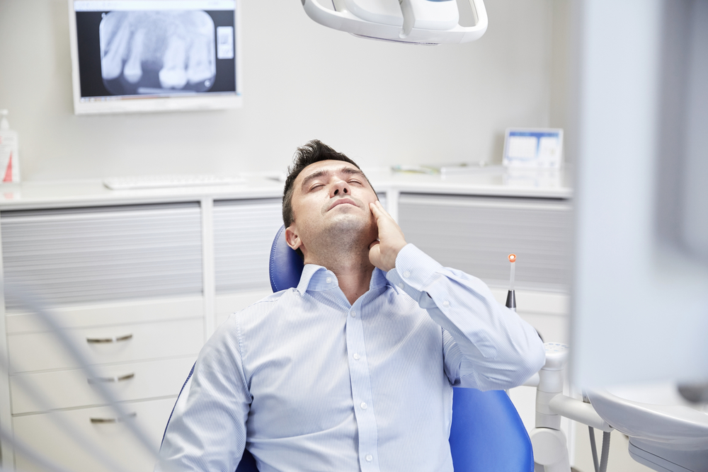 man with tooth ache in dental chair