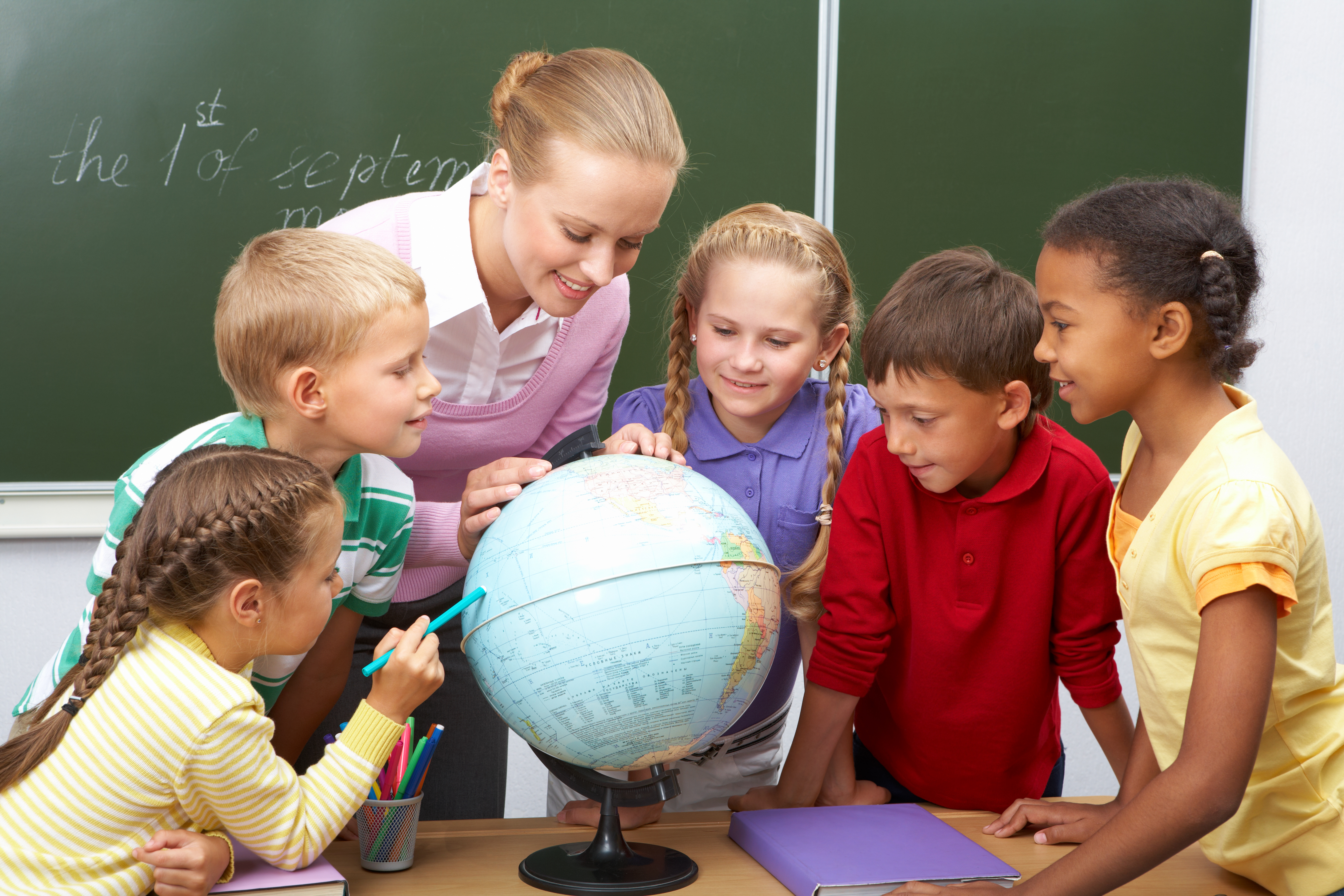 teacher with students looking at a globe