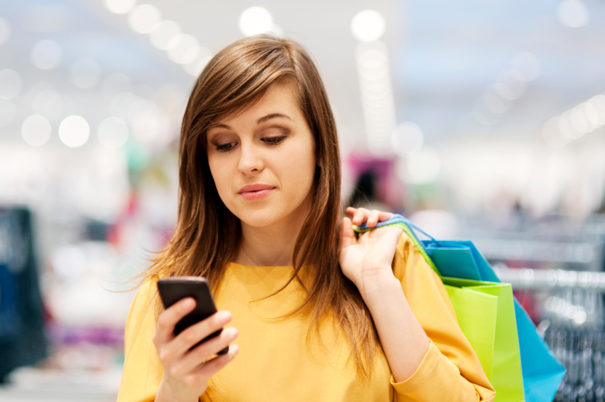 woman shopping while looking at cell phone